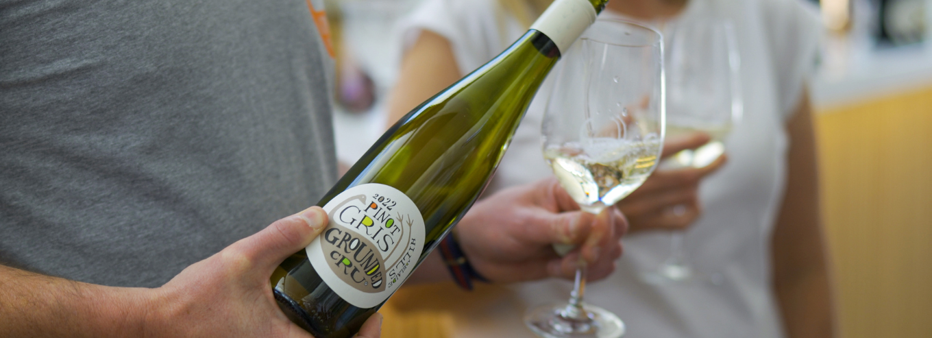 A man pouring a bottle of Grounded Cru Pinot Gris 2022 